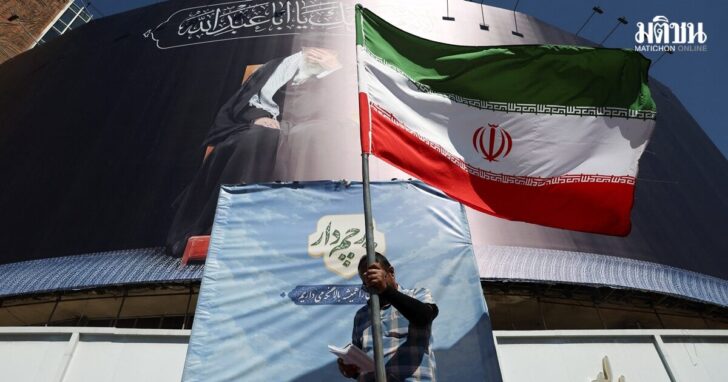 A man holds an Iranian flag on a street, in Tehran อิหร่าน
