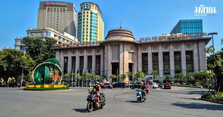 FILE PHOTO: People ride motorcycles in front of the headquarter of the State Bank of Vietnam in Hanoi