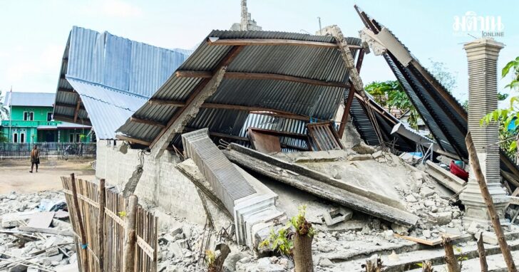 A person walks near a heavily-damaged house after an earthquake felt in Nanga Mbaur Village, East Manggarai, East Nusa Tenggara province