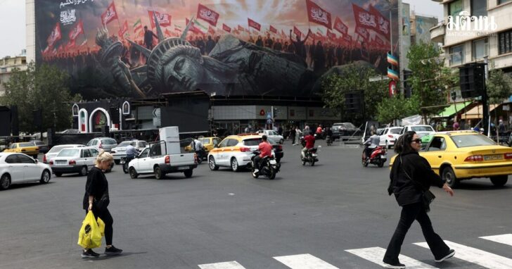 People walk past an anti-U.S. billboard on a street in Tehran