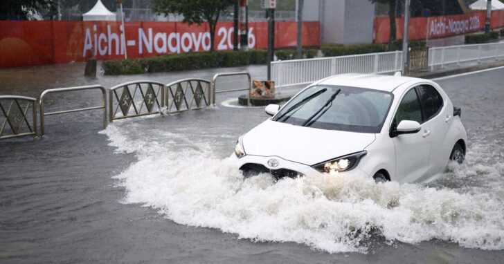 A car drives along a road flooded by heavy rain in Nagoya