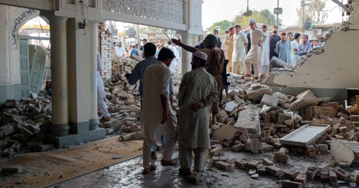 People gather at a damaged mosque following a suicide attack at a police facility in Kohat