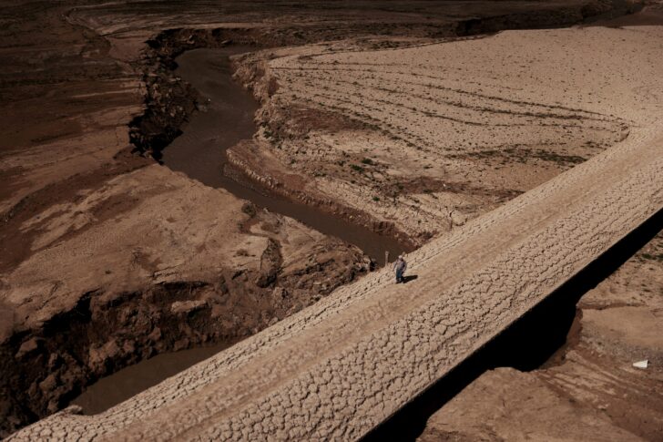 FILE PHOTO: A man walks on the cracked ground of the Baells reservoir